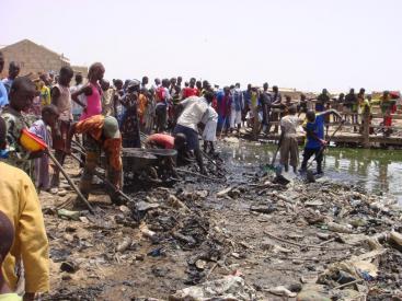Due to absence of waste management, these community members in a semi-formal settlement in Kaolack, Senegal, are cleaning their water streamfrom solid waste. As access to clean water also has to do with dignity, this can also be seen as an act to restore their own dignity. (Source: R. TRATSCHIN)